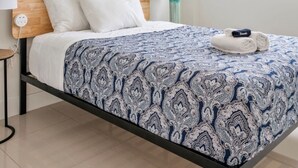 Ein Hotelzimmer mit einem Bett, zwei Wandlampen und zwei abstrakten Gemälden.