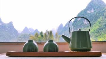 A wooden table with a tray holding three green teapots and a larger green teapot with a handle.