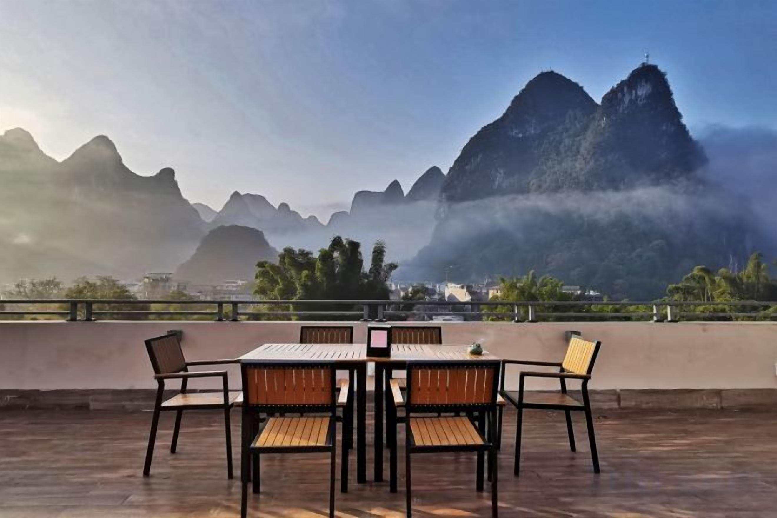 Una terraza con una mesa y sillas, con vistas a un paisaje montañoso.