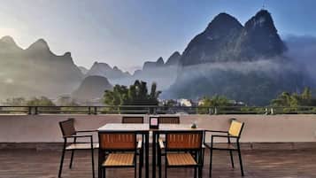 A terrace with a table and chairs, overlooking a mountainous landscape.