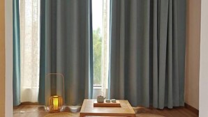 Una habitación con un ventanal grande, una mesa de madera con una bandeja y un candelabro.