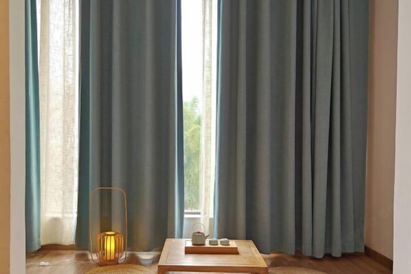 Ein Zimmer mit einem großen Fenster, einem Holztisch mit Tablett und einem Kerzenhalter.