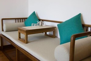 Eine Holzbank mit einem kleinen Tisch und türkisfarbenen Kissen.