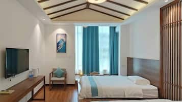 A modern hotel room with a wooden ceiling, a flat-screen TV, a comfortable chair, a bed with a striped bedspread, and a large window with blue curtains.