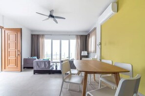 Une chambre d’hôtel équipée d’un lit, d’un bureau, d’une chaise, d’une table, d’un ventilateur de plafond et de grandes fenêtres.