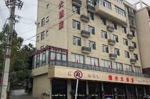 Un hotel de varios pisos con balcones y un restaurante a nivel de calle.