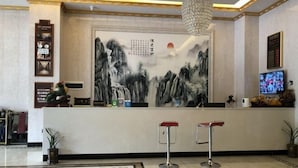 Een receptiegedeelte met een traditioneel Chinees schilderij, een kroonluchter en een televisiescherm.
