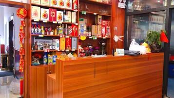 Een receptiebalie met een houten afwerking, planken vol diverse producten en een glazen vitrine.