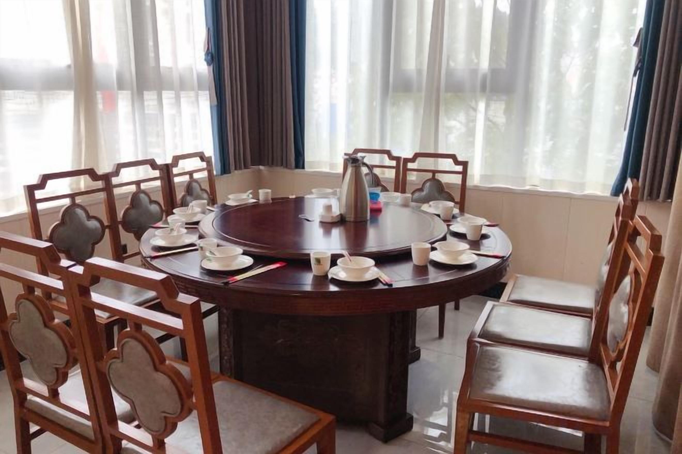 A round dining table with chairs, a coffee pot, and cups.
