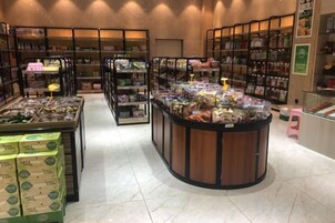 Interior de loja com prateleiras repletas de produtos, uma área de exposição central e um balcão de atendimento.