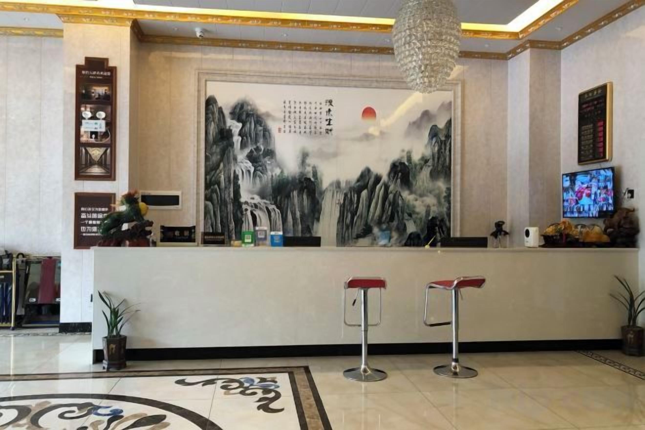 A reception area with a large wall painting, a television, and two bar stools.