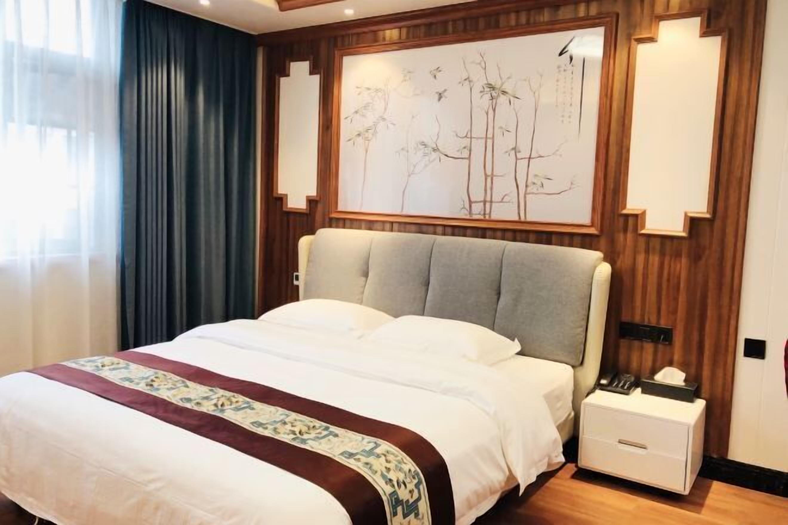 A hotel room with a large bed, a bedside table, and a wall-mounted artwork.