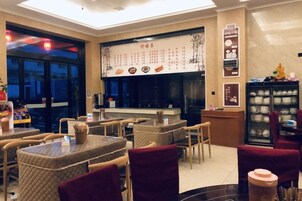 Interior de un restaurante con mesas, sillas, una pizarra de menú y un refrigerador.