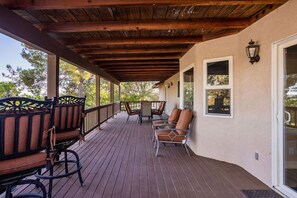 A covered outdoor area with wooden flooring, a table, and several chairs.