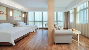A hotel room with two beds, a sofa, a small table, and large windows. - Vienna International Hotel (Qidong Jiangtian Ecological Park) (Qidong)