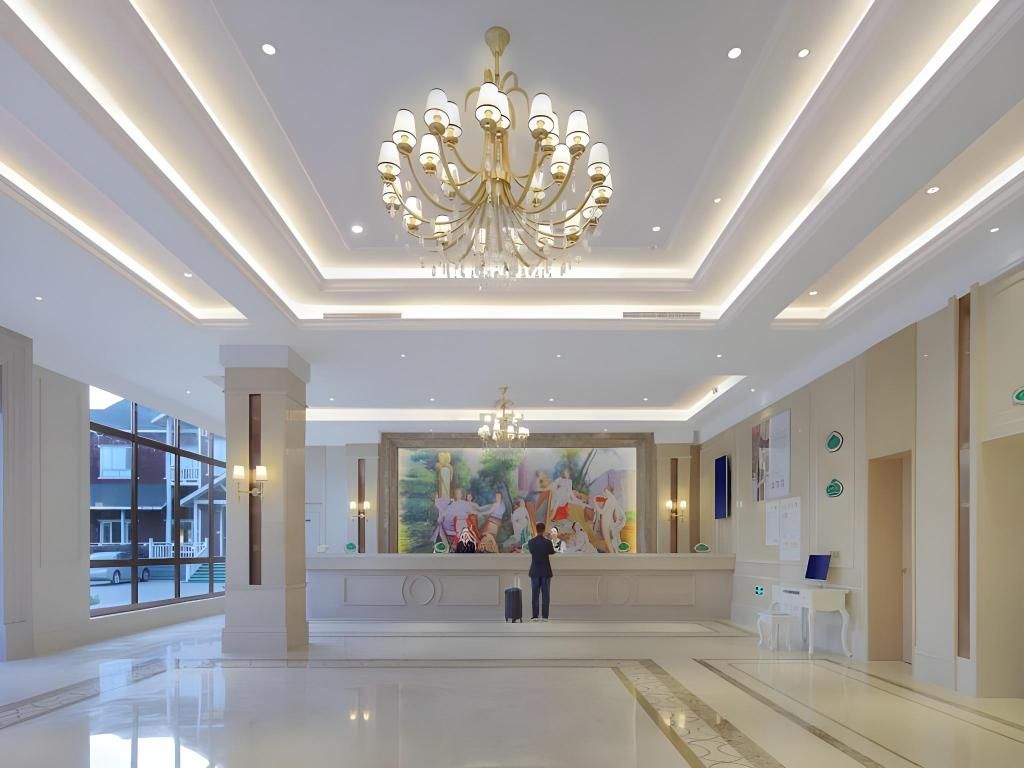 A spacious lobby with a chandelier, a large painting, and a reception desk.