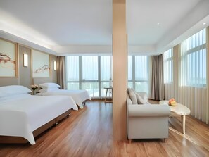 A hotel room with two beds, a sitting area, and large windows. - Vienna International Hotel (Qidong)