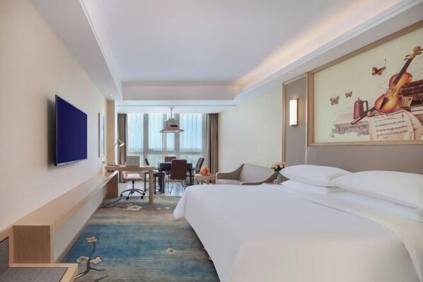 A hotel room with a large bed, a desk, a chair, and a television. - Vienna International Hotel (Qidong)