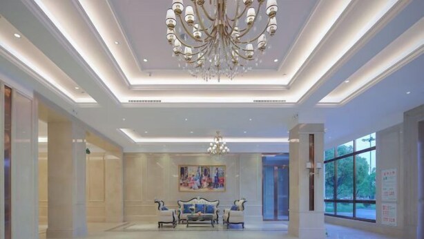 A spacious lobby with a chandelier, a painting on the wall, and a seating area with sofas. - Vienna International Hotel (Qidong Jiangtian Ecological Park) (Qidong)