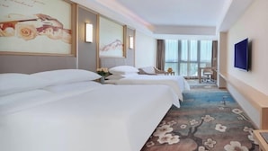 A hotel room with two beds, a large window, a flat-screen TV, and a floral carpet. - Vienna International Hotel (Qidong)