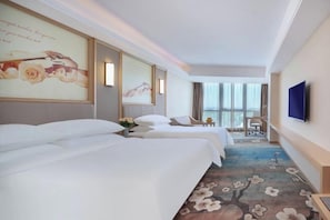 A hotel room with two beds, a large window, a flat-screen TV, and a floral carpet. - Vienna International Hotel (Qidong)