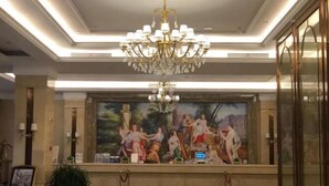 A lobby with a large mural, a chandelier, and a potted plant. - Vienna International Hotel (Qidong Jiangtian Ecological Park) (Qidong)