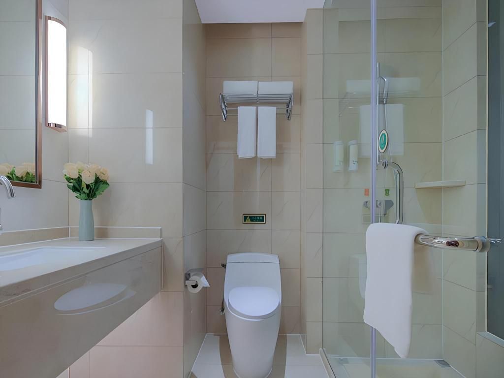 A modern bathroom with a glass shower enclosure, a toilet, and a sink with a vase of flowers.