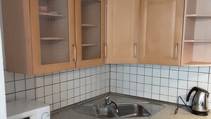 Eine kleine Küche mit Holzausstattung, einer Mikrowelle, einem Spülbecken und einem Wasserkocher.