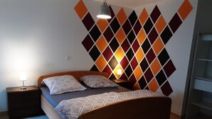 Ein Schlafzimmer mit einem hölzernen Bett, zwei Nachttischen, einer Wandlampe und einer Wand mit geometrischem Muster.