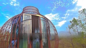 A spherical glass structure with a metal framework, surrounded by trees and a clear sky. - Lamangu Resort Hotel (Wugang)