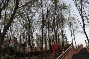 A wooden staircase leading up through a forested area with a view of a building in the background. - Lamangu Resort Hotel (Wugang)