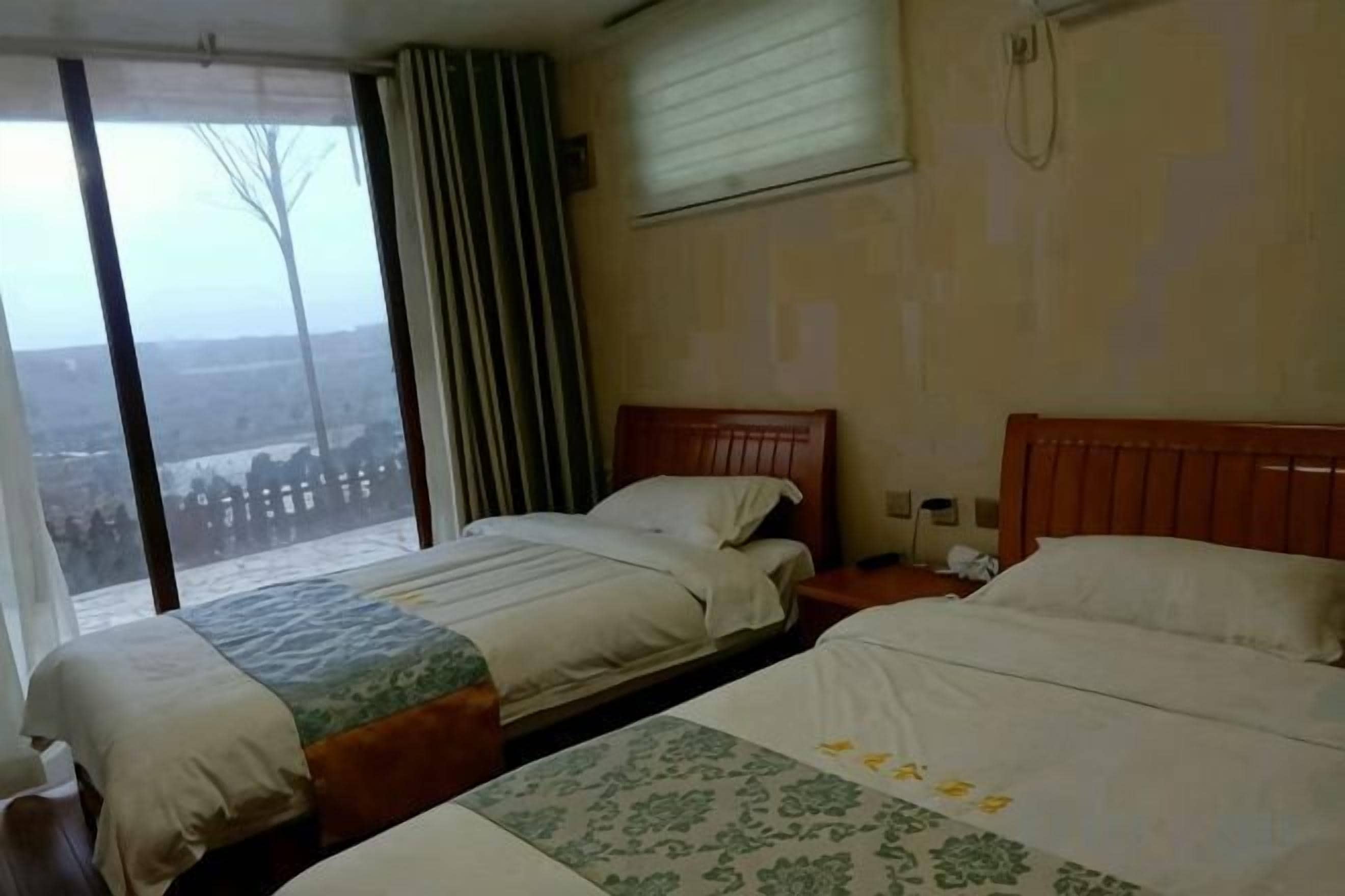 Quarto de hotel com duas camas, uma janela grande e vista para a paisagem.