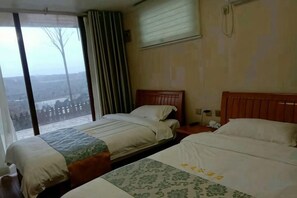 Quarto de hotel com duas camas, uma janela grande e vista para a paisagem.