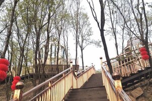 Una escalera de madera con barandilla metálica que sube a una plataforma.