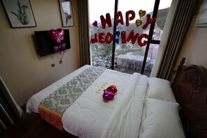 A hotel room with a bed, a window with a view, and a wall-mounted TV. - Lamangu Resort Hotel (Wugang)