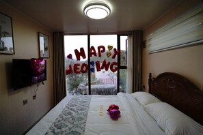 A hotel room with a bed, a flat-screen TV, a window with a view, and a 'HAPPY WEDDING' decoration. - Lamangu Resort Hotel (Wugang)