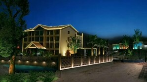 A multi-story hotel with a prominent entrance, a swimming pool, and a well-lit exterior. - Lamangu Resort Hotel (Wugang)