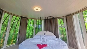 A bedroom with a curved ceiling, a bed with a white headboard, and large windows with curtains. - Lamangu Resort Hotel (Wugang)