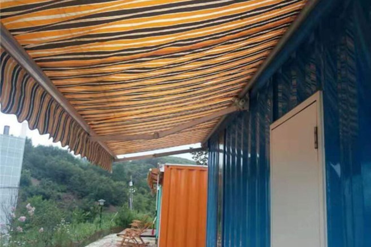 A covered outdoor area with a striped ceiling, a blue wall, and a white door.