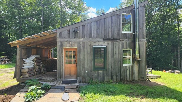 A rustic wooden cabin with a porch, a chimney, and a small garden area. - Cabin Retreat in Southern Vermont (Putney)