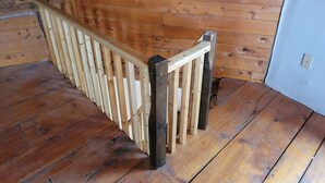 A wooden deck with a railing, wooden walls, and a white door. - Cabin Retreat in Southern Vermont (Putney)