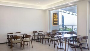 A dining area with multiple tables and chairs, a large window with a view, and a wall-mounted sign. - MU YI (Zhoushan)