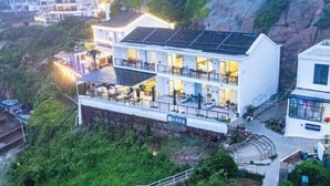 A modern hotel with multiple floors, large windows, and a rooftop terrace. - MU YI (Zhoushan)