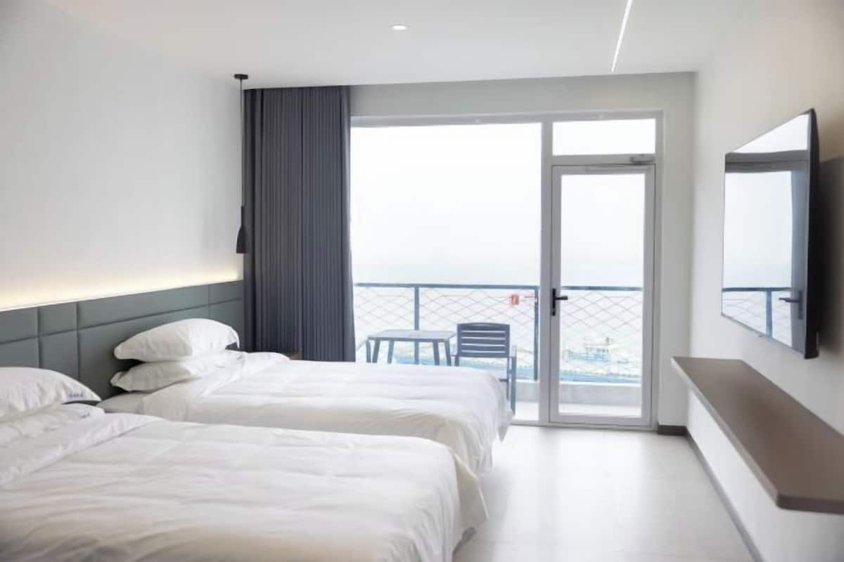 Ein modernes Hotelzimmer mit zwei Betten, einem großen Fenster und einem Balkon.