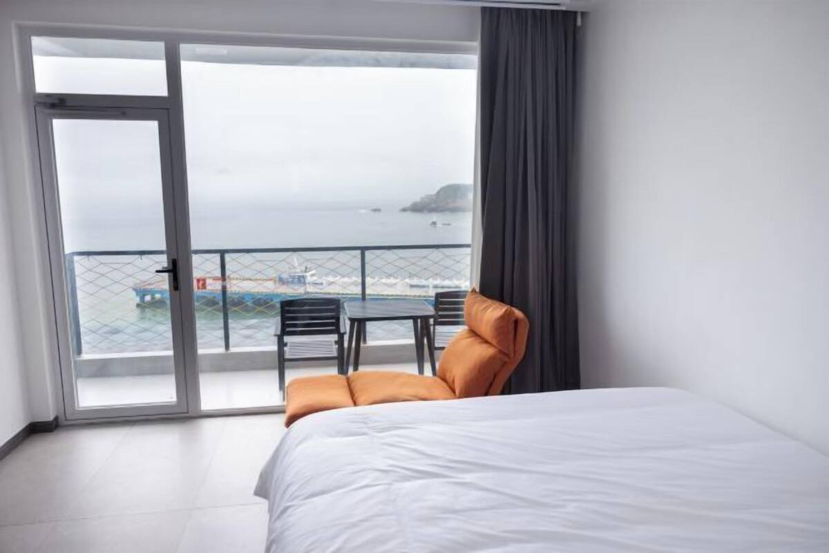 Ein Hotelzimmer mit Bett, Sessel, Tisch und Meerblick.