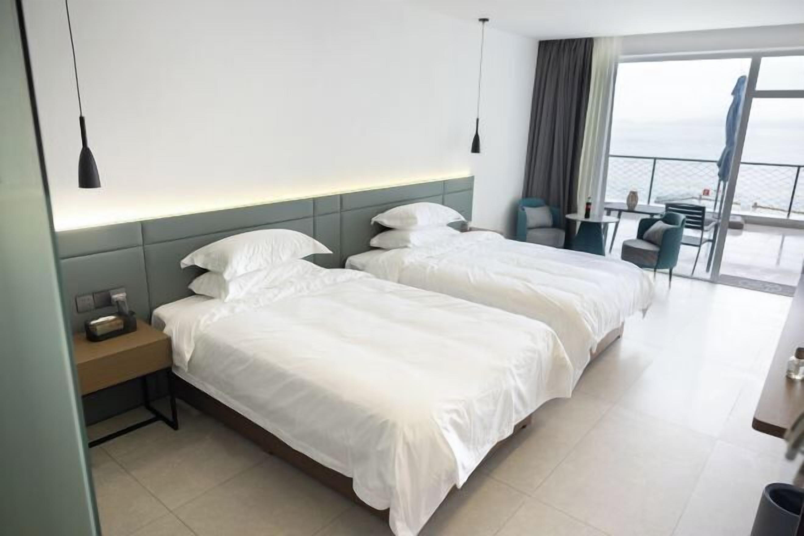 Ein Hotelzimmer mit zwei Betten, einem Schreibtisch und Blick aufs Meer.
