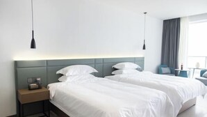 A hotel room with two beds, a nightstand, a lamp, and a window with curtains. - MU YI (Zhoushan)