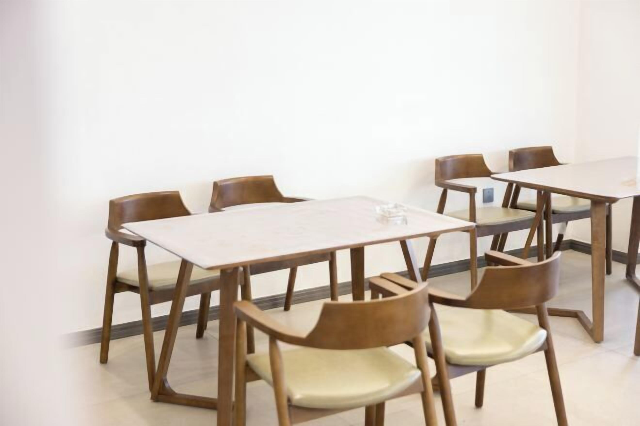 A conference room with a long table and six wooden chairs.