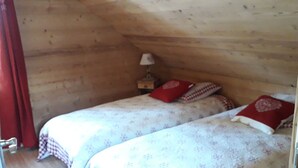 Ein kleines, gemütliches Zimmer mit Holzwänden und zwei Betten mit Blumenmuster-Bettwäsche.