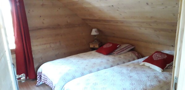 Ein kleines, gemütliches Zimmer mit Holzwänden und zwei Betten mit Blumenmuster-Bettwäsche.